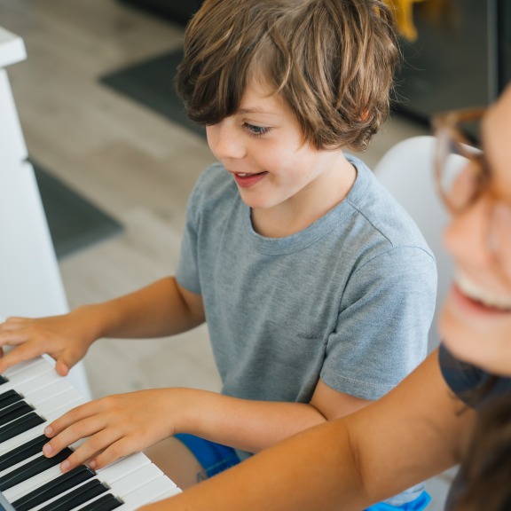 Young student playing piano with teacher